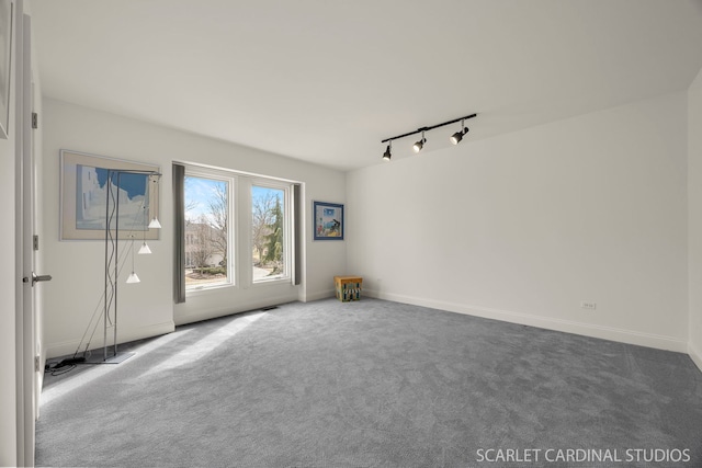unfurnished room with baseboards, rail lighting, and carpet floors