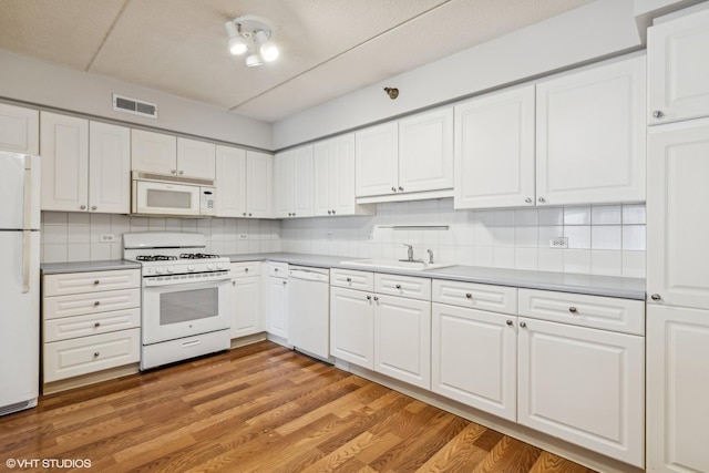 kitchen with white appliances, visible vents, a sink, white cabinetry, and light wood-type flooring