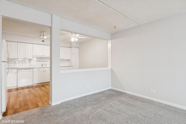 unfurnished room with baseboards, a textured ceiling, and light carpet