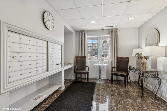 living area featuring mail area, marble finish floor, a drop ceiling, recessed lighting, and baseboards