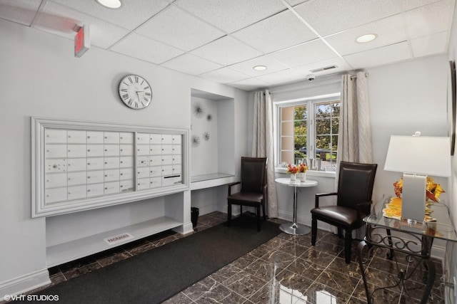 sitting room featuring a drop ceiling, marble finish floor, mail area, and baseboards