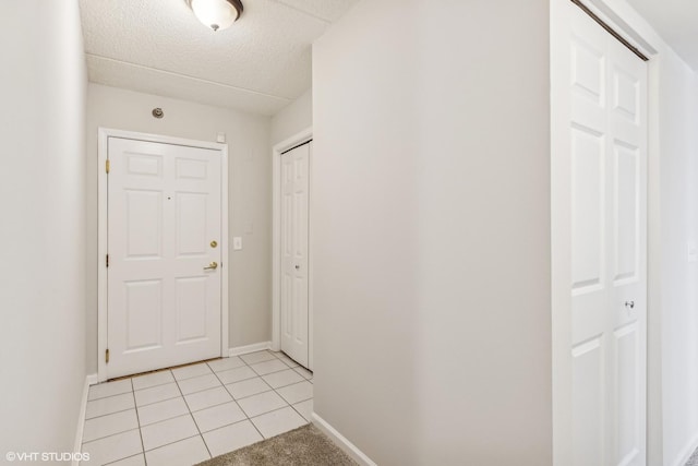 interior space featuring light tile patterned flooring, a textured ceiling, and baseboards