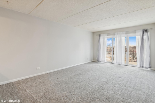 spare room with a textured ceiling, baseboards, and carpet floors