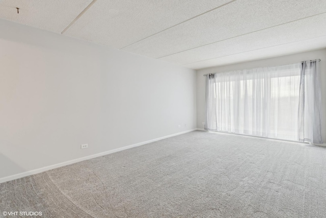 carpeted spare room with a textured ceiling and baseboards