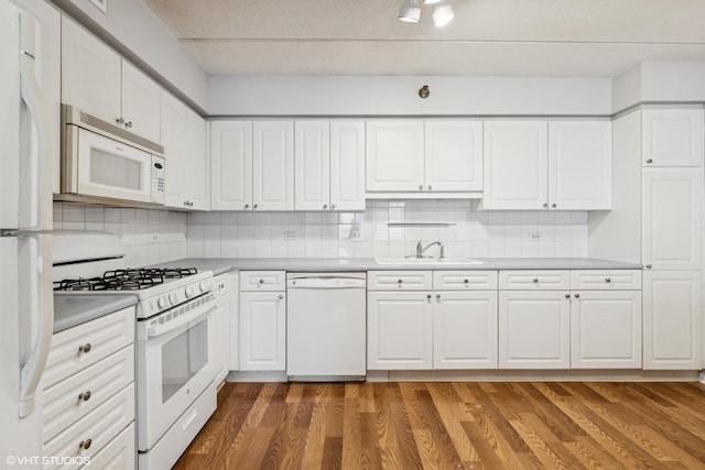 kitchen featuring backsplash, light wood-type flooring, white appliances, white cabinetry, and a sink