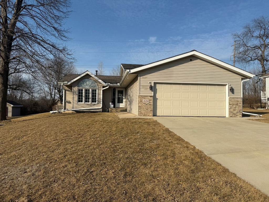 single story home with brick siding, a garage, concrete driveway, and a front yard