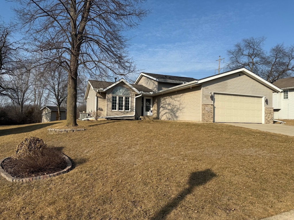 ranch-style house featuring concrete driveway, a garage, brick siding, and a front yard