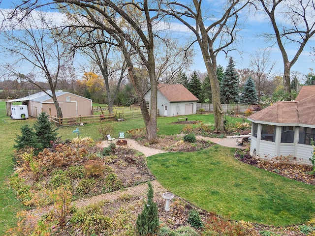 view of yard featuring an outbuilding, a garage, an outdoor structure, and fence