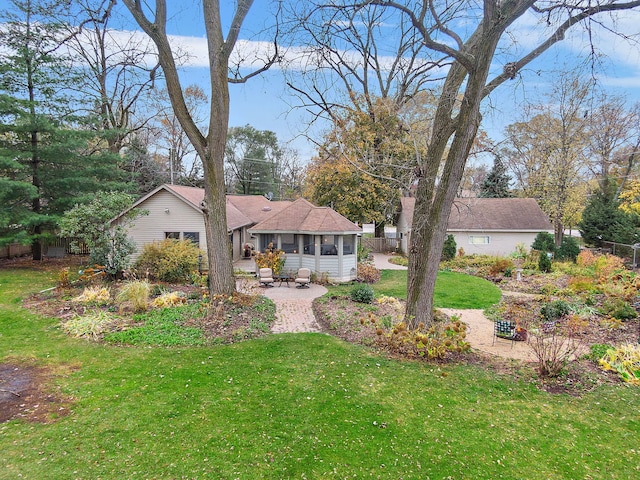 view of front facade with a sunroom, fence, a front yard, and a patio area