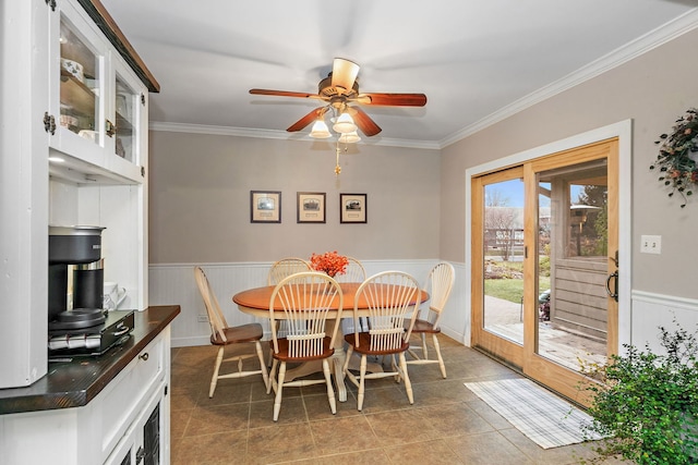 dining room featuring a ceiling fan, a wainscoted wall, and ornamental molding