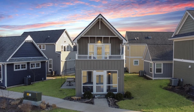 view of front facade featuring a front lawn, cooling unit, board and batten siding, and a sunroom