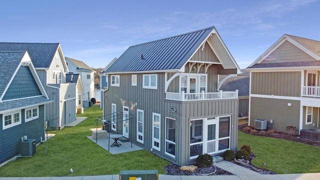 rear view of property with a standing seam roof, a yard, a sunroom, board and batten siding, and metal roof