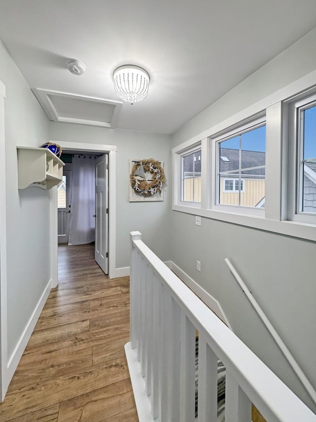 hall with attic access, wood finished floors, an upstairs landing, and baseboards