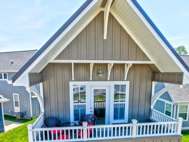 exterior space featuring board and batten siding, central AC, and a shingled roof