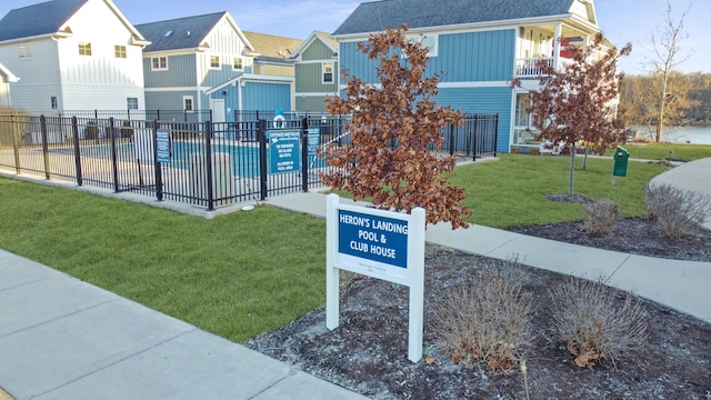 surrounding community featuring a residential view, a lawn, a pool, and fence