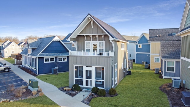 back of house featuring central AC, a yard, board and batten siding, a sunroom, and a balcony