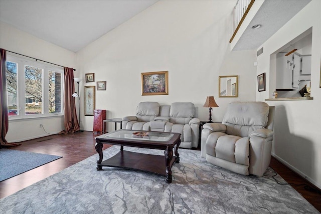 living room featuring wood finished floors, baseboards, and high vaulted ceiling