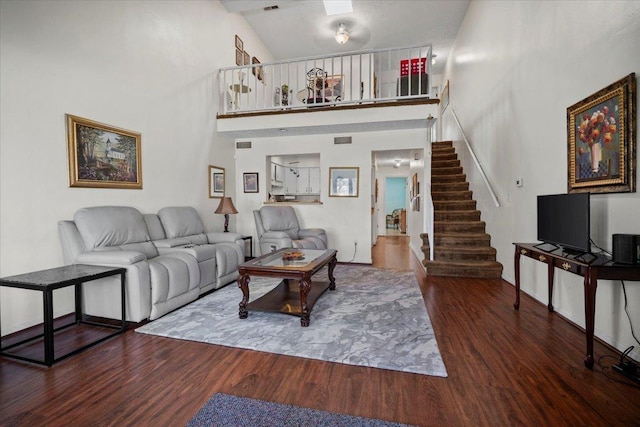 living area featuring visible vents, stairs, a towering ceiling, and wood finished floors