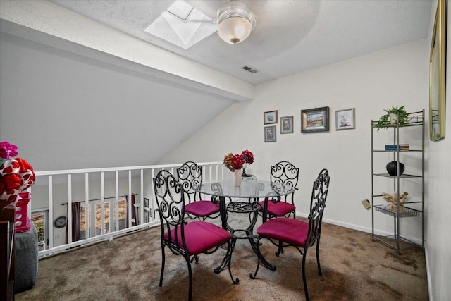 carpeted dining space with visible vents, vaulted ceiling with skylight, and baseboards