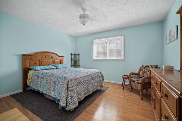 bedroom featuring baseboards, a textured ceiling, and light wood finished floors