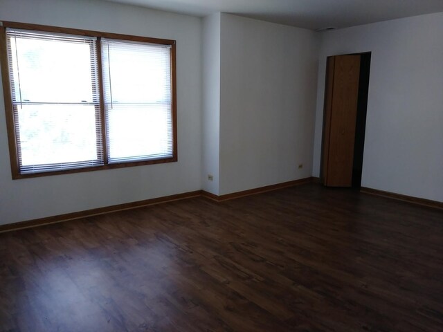 unfurnished room featuring baseboards and dark wood-style floors