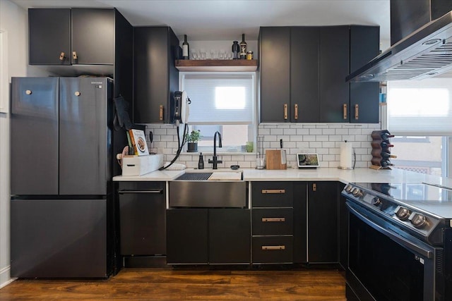 kitchen with black range with electric stovetop, light countertops, freestanding refrigerator, and extractor fan