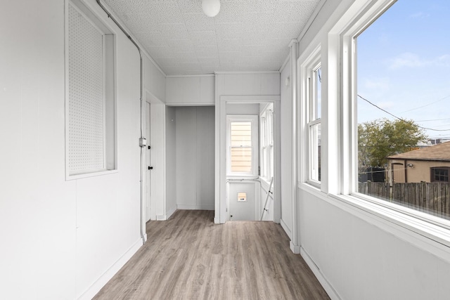 corridor with baseboards and light wood-type flooring