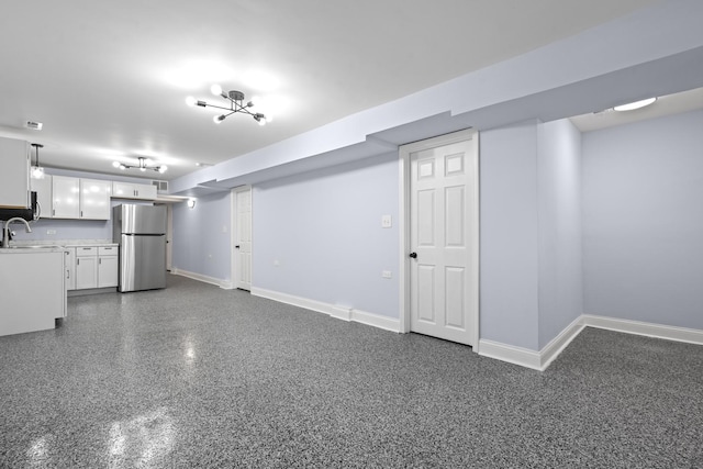 finished below grade area featuring baseboards, freestanding refrigerator, and a sink