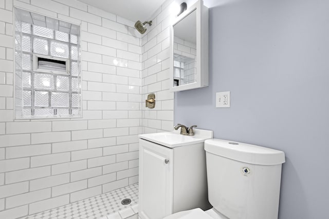 full bath featuring a tile shower, toilet, and vanity