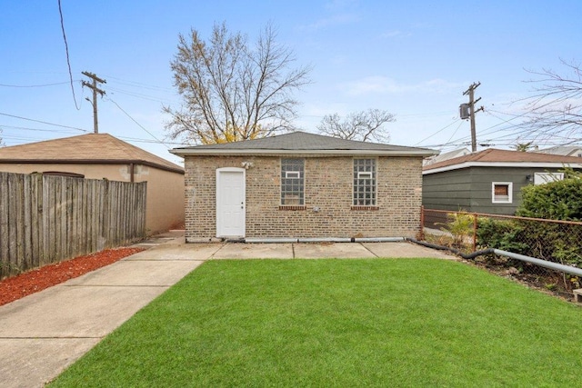 back of house with a yard, an outbuilding, brick siding, and fence private yard