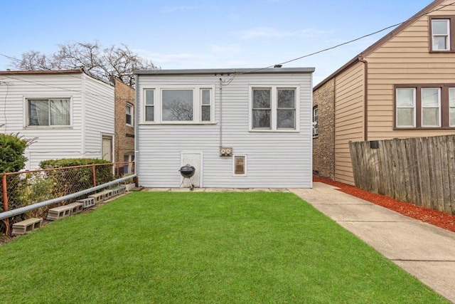 rear view of house with a lawn and a fenced backyard