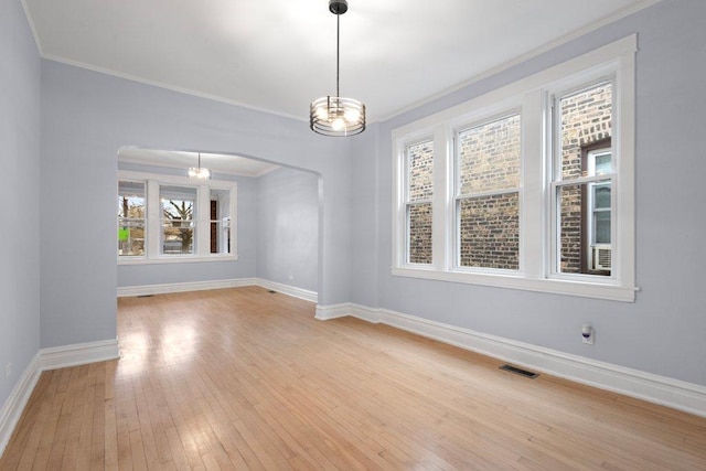 unfurnished room with visible vents, arched walkways, wood-type flooring, and baseboards