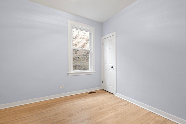 spare room featuring visible vents, light wood-type flooring, and baseboards