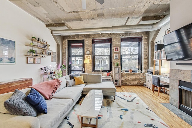 living area featuring plenty of natural light, wood finished floors, and brick wall