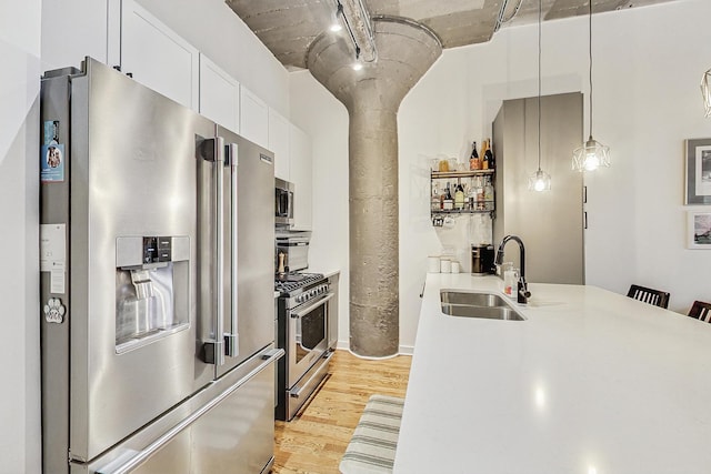 kitchen with light wood-style flooring, a sink, stainless steel appliances, light countertops, and white cabinetry