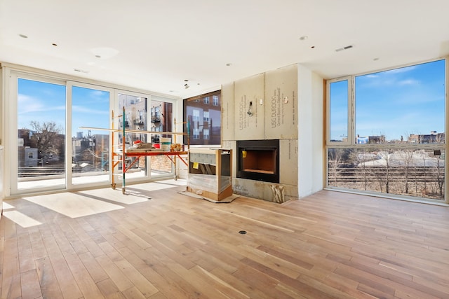 unfurnished living room featuring visible vents, floor to ceiling windows, a fireplace, and wood finished floors