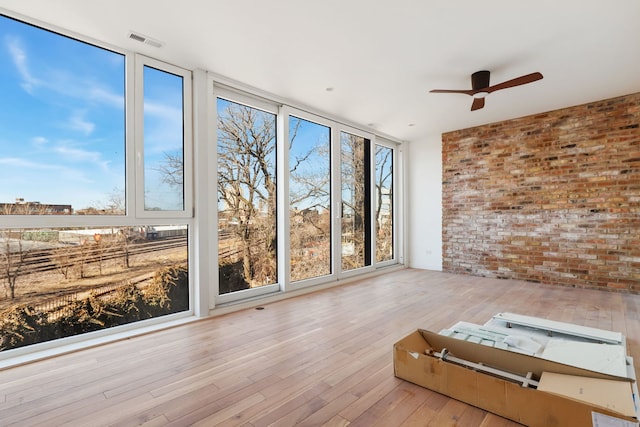 unfurnished sunroom featuring visible vents and ceiling fan