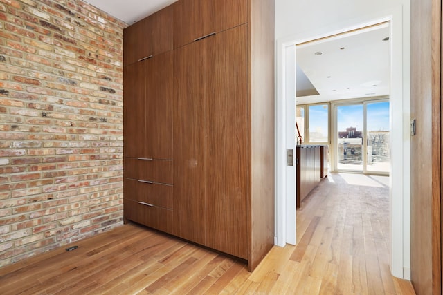 interior space with light wood finished floors, brick wall, and expansive windows