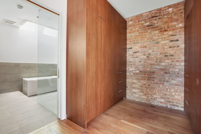 interior space with light wood-style floors and brick wall