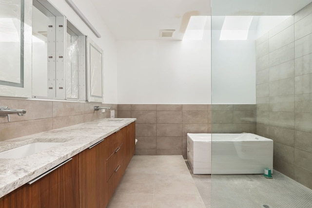 bathroom featuring visible vents, double vanity, a sink, tile walls, and tile patterned floors