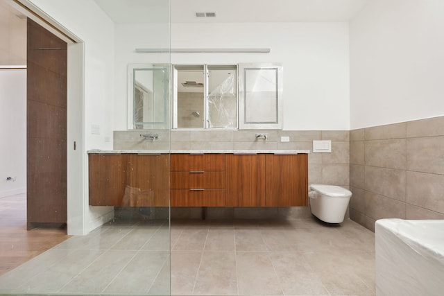 bathroom featuring visible vents, toilet, tile walls, tile patterned flooring, and double vanity