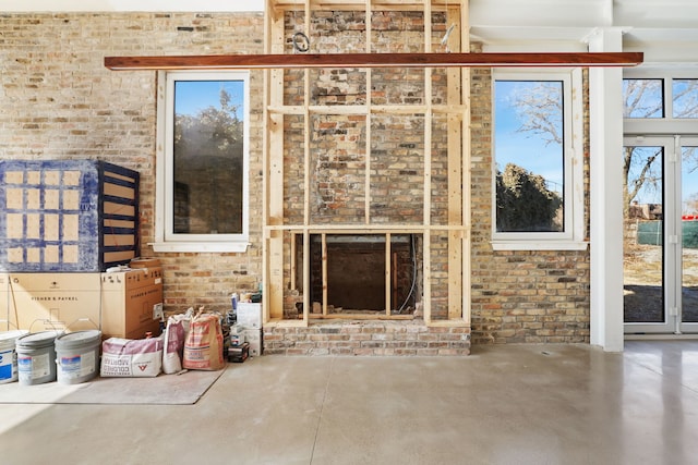 unfurnished living room featuring concrete floors and brick wall