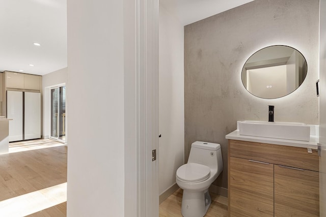 bathroom with recessed lighting, wood finished floors, toilet, and vanity