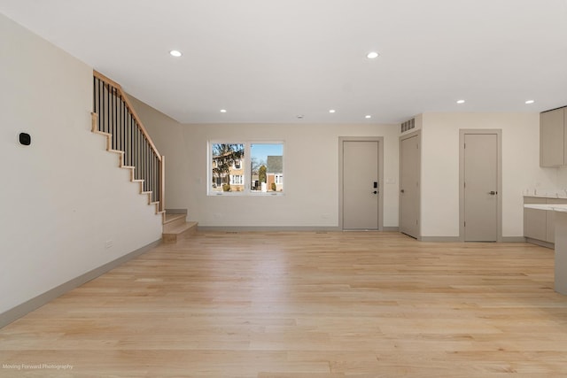 unfurnished living room with recessed lighting, light wood-type flooring, visible vents, and stairway
