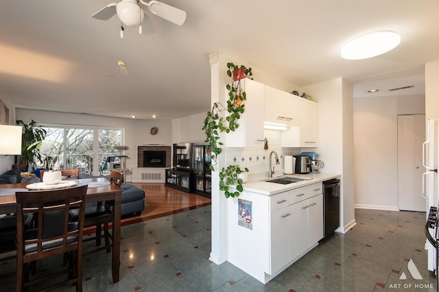 kitchen featuring visible vents, a fireplace with raised hearth, open floor plan, black dishwasher, and a sink