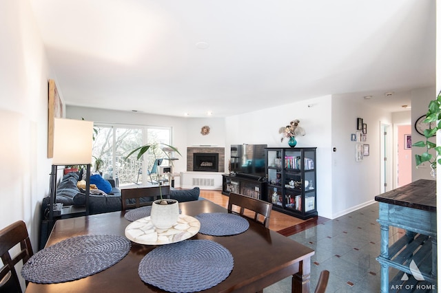 dining space with a fireplace with raised hearth and baseboards