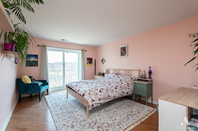 bedroom featuring visible vents, baseboards, and wood finished floors