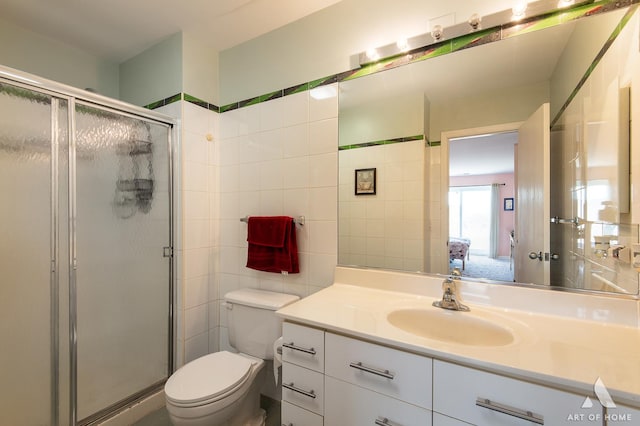 bathroom with toilet, tile walls, a stall shower, and vanity