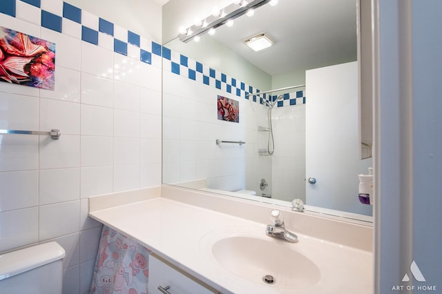 bathroom with a shower, vanity, toilet, and tile walls