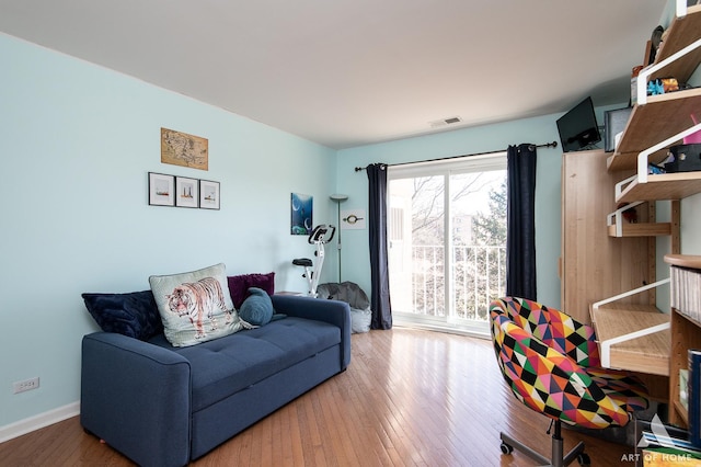 living room with visible vents, baseboards, and wood finished floors